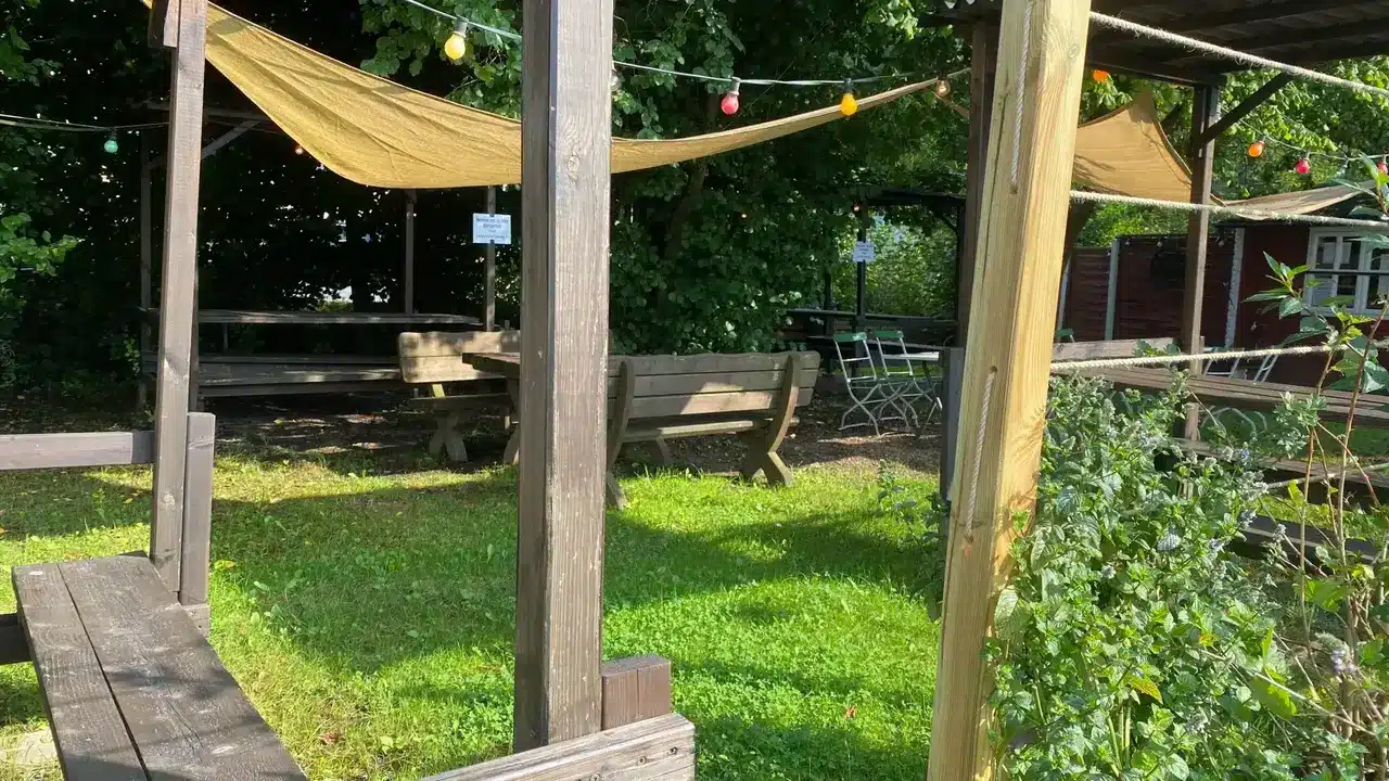 Biergarten mit Bierbänken und Sonnensegel im Grünen